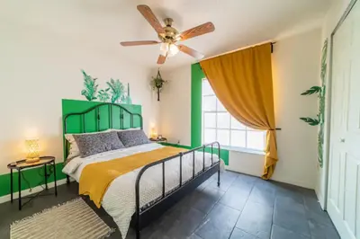 a bedroom with a bed with a green headboard and a ceiling fan at Newly Updated 3 Bedroom Home in Kissimmee