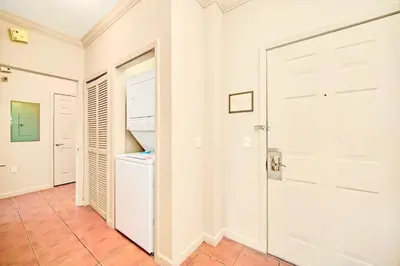 a hallway with a white door and a refrigerator at Stunning 2BR Condo with Pool, near Disney! in Orlando