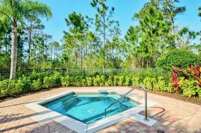 a hot tub in a brick patio with trees in the background at Stunning 2BR Condo with Pool, near Disney! in Orlando