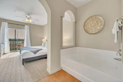a white bathroom with a tub and a bed at 2BR Condo with pool, near Disney! in Orlando