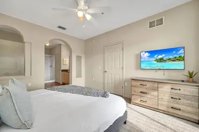 a bedroom with a white bed and a flat screen tv at 2BR Condo with pool, near Disney! in Orlando