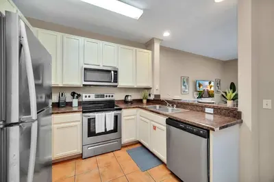 a kitchen with white cabinets and stainless steel appliances at Bright 3BR Condo With Pool, Close to Disney! in Orlando