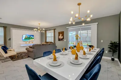 a dining room with a white table and blue chairs at Mickey Mouse ClubHouse 8min Disneyworld Pool Spa Sleeps 20 in Kissimmee
