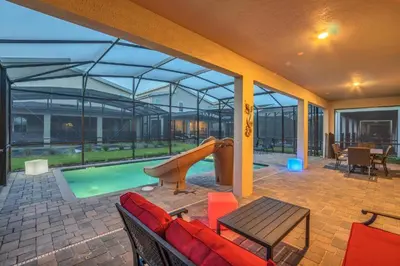 a patio with a slide and a swimming pool at Mickey Mouse ClubHouse 8min Disneyworld Pool Spa Sleeps 20 in Kissimmee