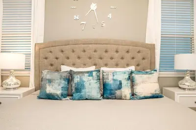 a bedroom with a bed with pillows and a clock on the wall at Mickey Mouse ClubHouse 8min Disneyworld Pool Spa Sleeps 20 in Kissimmee