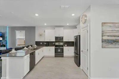 a large kitchen with white cabinets and black appliances at Amazing Family Home 8min Disneyworld Pool/Spa Sleeps 24 in Kissimmee