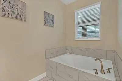 a white bathroom with a tub and a window at Magical Family Home 8min Disneyworld Pool/Spa Sleeps 22 in Kissimmee
