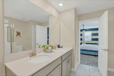 a bathroom with two sinks and a bedroom at Magical Family Home 8min Disneyworld Pool/Spa Sleeps 22 in Kissimmee