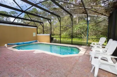 a swimming pool in a greenhouse with two chairs and a table at Peaceful Quiet Pool Home 5 min from Disney! townhouse in Orlando