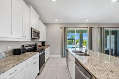 a kitchen with white cabinets and granite counter tops at Alluring Home With Private Pool And Waterpark & Resort Access Near Disney At Encore Resorts Reunion - 280Sf in Kissimmee