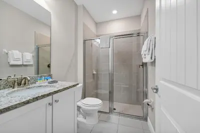 a white bathroom with a shower and a toilet at Alluring Home With Private Pool And Waterpark & Resort Access Near Disney At Encore Resorts Reunion - 280Sf in Kissimmee