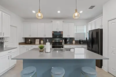 a kitchen with white cabinets and a large island with stools at Beautiful Family Villa - Pool and Hot Tub - Near Disney World in Kissimmee
