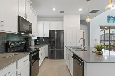 a kitchen with white cabinets and a stainless steel refrigerator at Beautiful Family Villa - Pool and Hot Tub - Near Disney World in Kissimmee