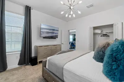 a bedroom with a bed and a tv on the wall at Beautiful Family Villa - Pool and Hot Tub - Near Disney World in Kissimmee