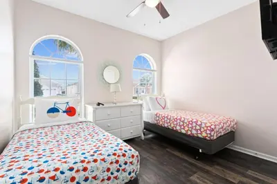 a bedroom with two beds and a dresser and two windows at South Facing Pool 4 Bedroom 3 Bath Villa villa in Kissimmee
