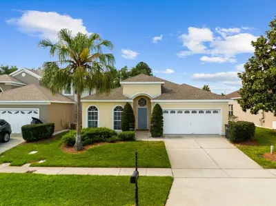 a house with a palm tree and a driveway at South Facing Pool 4 Bedroom 3 Bath Villa villa in Kissimmee