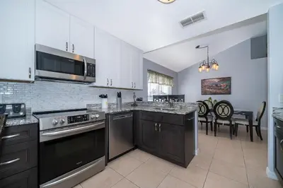 a kitchen with stainless steel appliances and a dining room at South Facing Pool with Stunning Lake View - Family Friendly Home - Nr Disney in Kissimmee