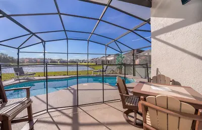 a view of a pool from a patio with a table and chairs at South Facing Pool with Stunning Lake View - Family Friendly Home - Nr Disney in Kissimmee