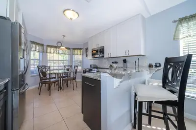 a kitchen with white cabinets and a table with chairs at South Facing Pool with Stunning Lake View - Family Friendly Home - Nr Disney in Kissimmee