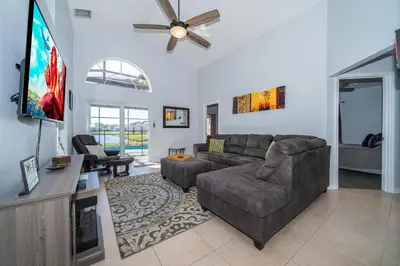 a living room with a couch and a flat screen tv at South Facing Pool with Stunning Lake View - Family Friendly Home - Nr Disney in Kissimmee