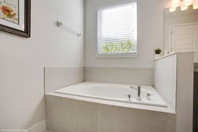a white bath tub in a bathroom with a window at Stylish Family Home Private Pool/Spa 10min Disneyworld Sleeps 22 in Orlando