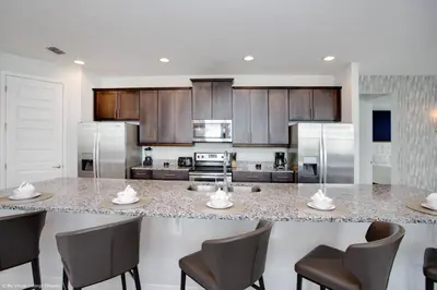 a kitchen with a large island with chairs in it at Stylish Family Home Private Pool/Spa 10min Disneyworld Sleeps 22 in Orlando