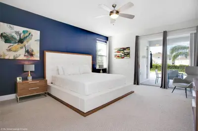 a bedroom with a white bed and a blue wall at Stylish Family Home Private Pool/Spa 10min Disneyworld Sleeps 22 in Orlando