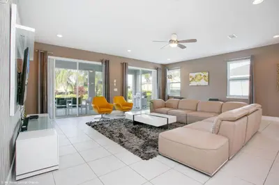a living room with a couch and yellow chairs at Stylish Family Home Private Pool/Spa 10min Disneyworld Sleeps 22 in Orlando