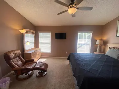 a bedroom with a bed and a chair and a ceiling fan at 3 Bedroom Villa with Poolside Cinema and Games Room Close to theme Parks sleeps 6 in Orlando