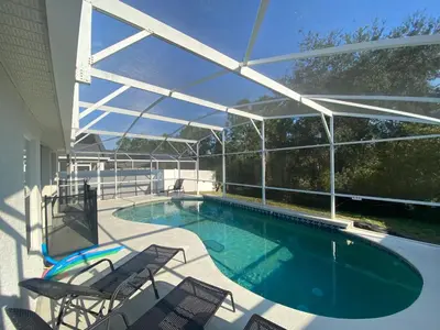 a swimming pool with chairs and a patio with a roof at 3 Bedroom Villa with Poolside Cinema and Games Room Close to theme Parks sleeps 6 in Orlando