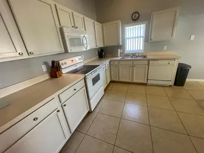 a kitchen with white cabinets and white appliances at 3 Bedroom Villa with Poolside Cinema and Games Room Close to theme Parks sleeps 6 in Orlando