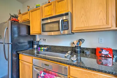 a kitchen with wooden cabinets and a stainless steel refrigerator at Disney-Inspired Townhome with Private Hot Tub! in Orlando
