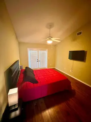 a bedroom with a red bed and a flat screen tv at Grand Villas of Island 3BR Condo near Disney Parks and Universal in Kissimmee