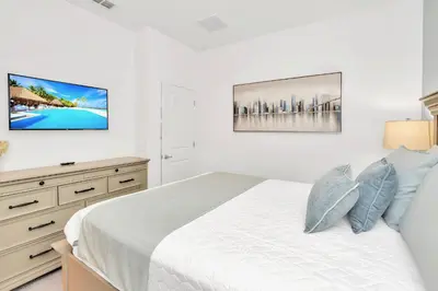 a white bedroom with a bed and a dresser at Upstay 9BR Disney Retreat w Pool, BBQ & Hot Tub in Kissimmee