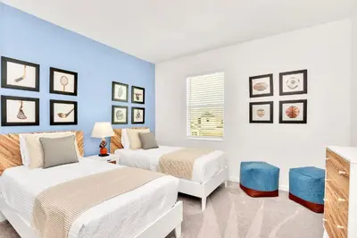 a bedroom with two beds and a blue wall at Upstay 9BR Disney Retreat w Pool, BBQ & Hot Tub in Kissimmee