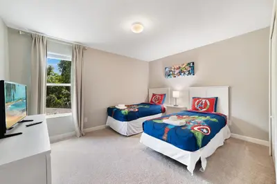 a bedroom with two beds and a tv and a window at Paradise Villa Disney Staycation Pool, Fun & Resort Access in Kissimmee