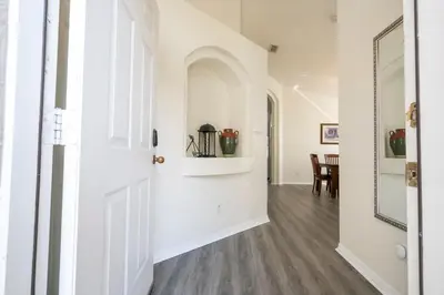 a hallway with white walls and wood floors and a mirror at 133 Beautiful home with lake view in Kissimmee