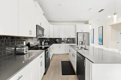a large kitchen with white cabinets and black appliances at Sophisticated 6BR at Storey Lake SL2766 in Kissimmee