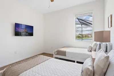 a white bedroom with two beds and a window at Ground Floor Gathering up to 9 guests BL387 in Kissimmee