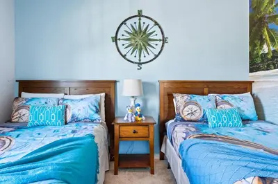 a bedroom with two beds and a table with a clock on the wall at 4BR Community pool across the street WL8989 in Kissimmee