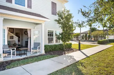 a white house with a porch with chairs and a table at 4BR Community pool across the street WL8989 in Kissimmee