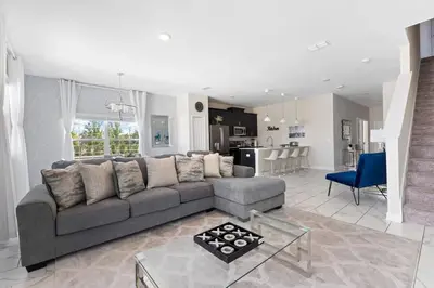 a living room with a gray couch and a kitchen at Disney Familly Lovers up to 11 SL4928 in Kissimmee