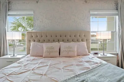 a bedroom with a bed with two pillows and two windows at Cute with Private Pool at Storey Lake SL4802 in Kissimmee