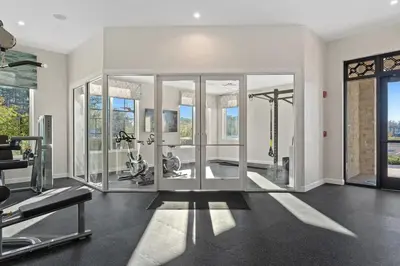 a gym with glass doors and exercise equipment in it at 4 BR Bright Cozy at Storey Lake SL3113 in Kissimmee