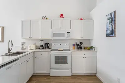 a white kitchen with white cabinets and appliances at 4 BR No carpet Just Remodeled Unit SR1205 in Kissimmee