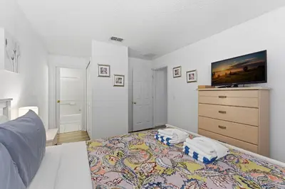 a bedroom with a bed and a dresser with a tv at 4 BR No carpet Just Remodeled Unit SR1205 in Kissimmee
