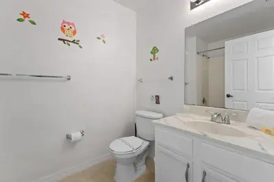 a white bathroom with a toilet and a sink at Relaxing 3BR Haven for 8 at Seven Dwarfs SD2610 in Kissimmee