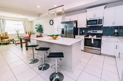 a kitchen with white cabinets and a island with bar stools at 2 BR Modern Apt near Disney SL4741 in Kissimmee