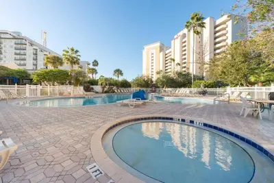 a swimming pool with tables and chairs and buildings at Studio near Universal Studios with great view in Orlando