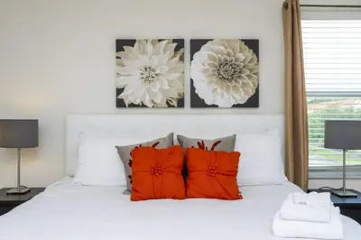 a bedroom with a white bed with orange pillows at 4572 Perfect home for your family close to all parks in Kissimmee